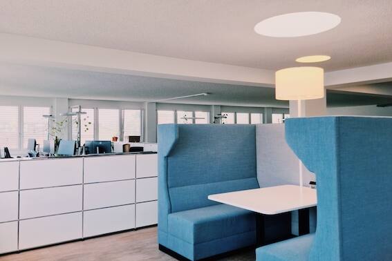 Modernes Büro mit blauem Rückzugbereich, Sofa (Diner), Elektrik, Lampe und Tisch.