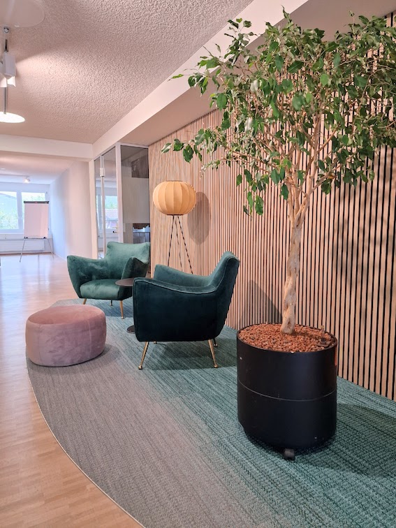 Modernes Büro mit Besprechungsnischen. Grüne Sessel mit Elementen aus der Natur.