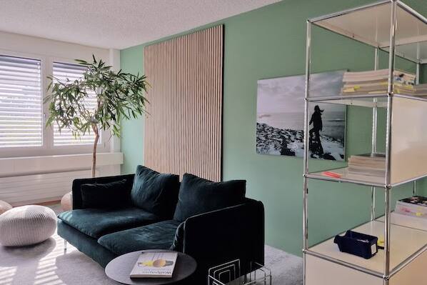 Einladend und modern gestaltetes USM-Buchregal im Büro mit Holzpaneelen, grün-grauem Ambiente von der Natur inspiriert.