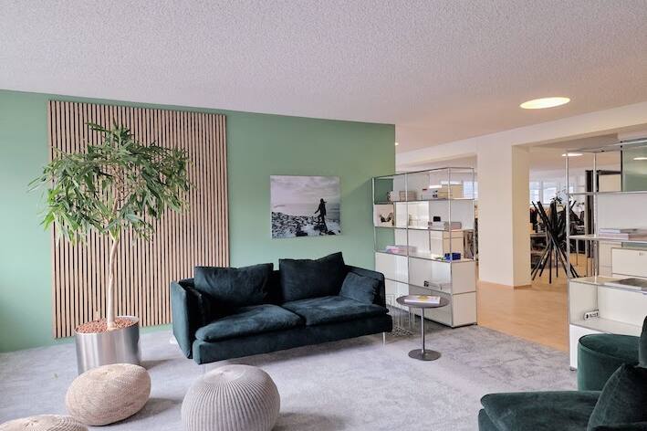 Einladend und modern gestaltetes USM-Buchregal im Büro mit Holzpaneelen, grün-grauem Ambiente von der Natur inspiriert.