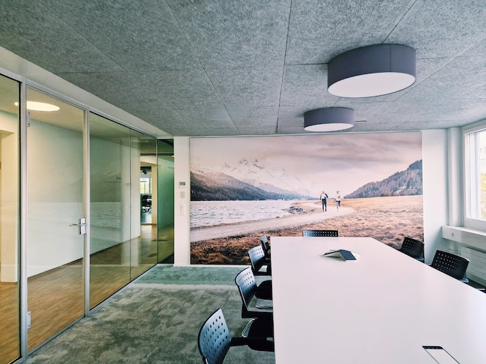 Sitzungszimmer mit XXL-Bild und grün-grauem Fliesenteppich, weisser Vitra Tisch