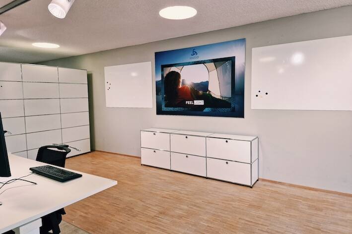 Geräumiger Projektraum mit Whiteboards, höhenverstellbaren Schreibtischen und modernen Drehstühlen für produktives Arbeiten.