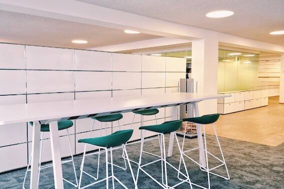 Innovations-Raum mit grauem Interface Teppich, Hochtisch mit grünen Hay Stühlen und weisse Magnet-USM-Wand